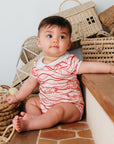 Bébé assis sur des marches en extérieur, portant le body bébé imprimé Bandia de Bobo Bassari, conçu avec un tissu doux et un design inspiré des motifs africains