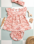 Ensemble robe imprimée Bandia de Bobo Bassari, vue de face, mettant en valeur les motifs roses et les détails soignés de la robe, du bandeau et du bloomer