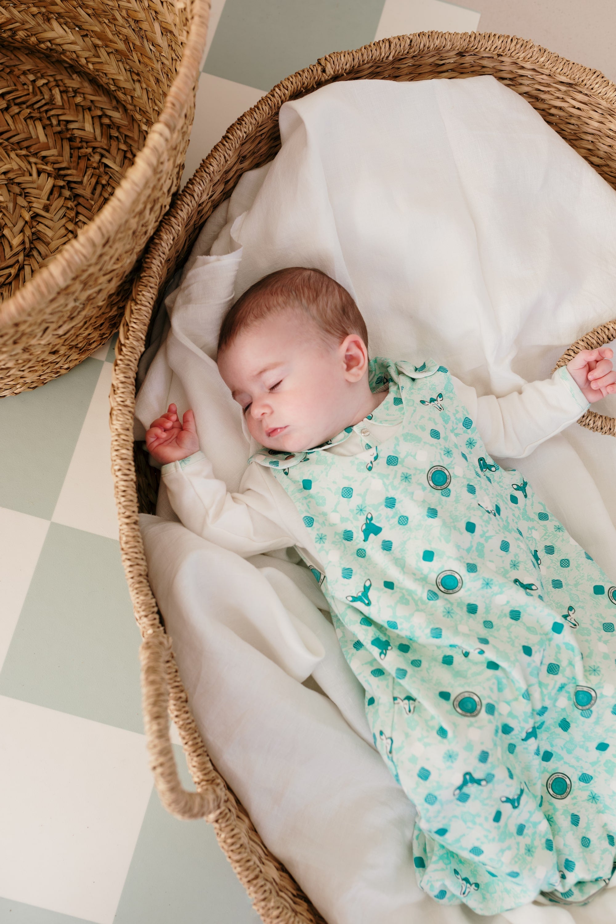 Bébé allongé dans un panier en rotin, habillé de la gigoteuse bébé été imprimée Samé de Bobo Bassari, conçue pour un confort optimal pendant les nuits d’été