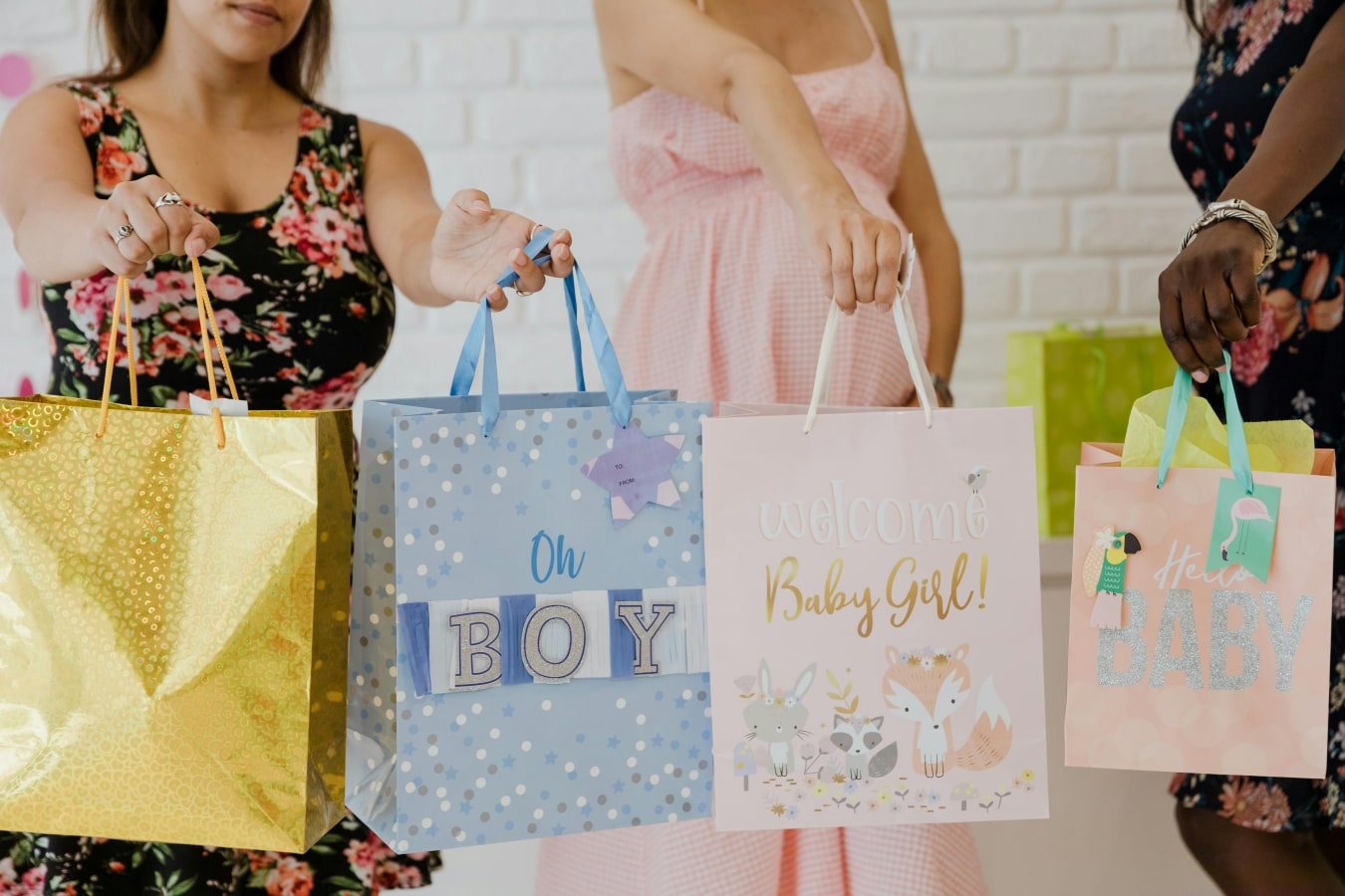 Plusieurs femmes souriantes tendent des sacs de cadeaux de naissance colorés, mettant en avant des créations uniques et inspirées de la culture Bobo Bassari, parfaites pour célébrer l'arrivée d'un nouveau-né